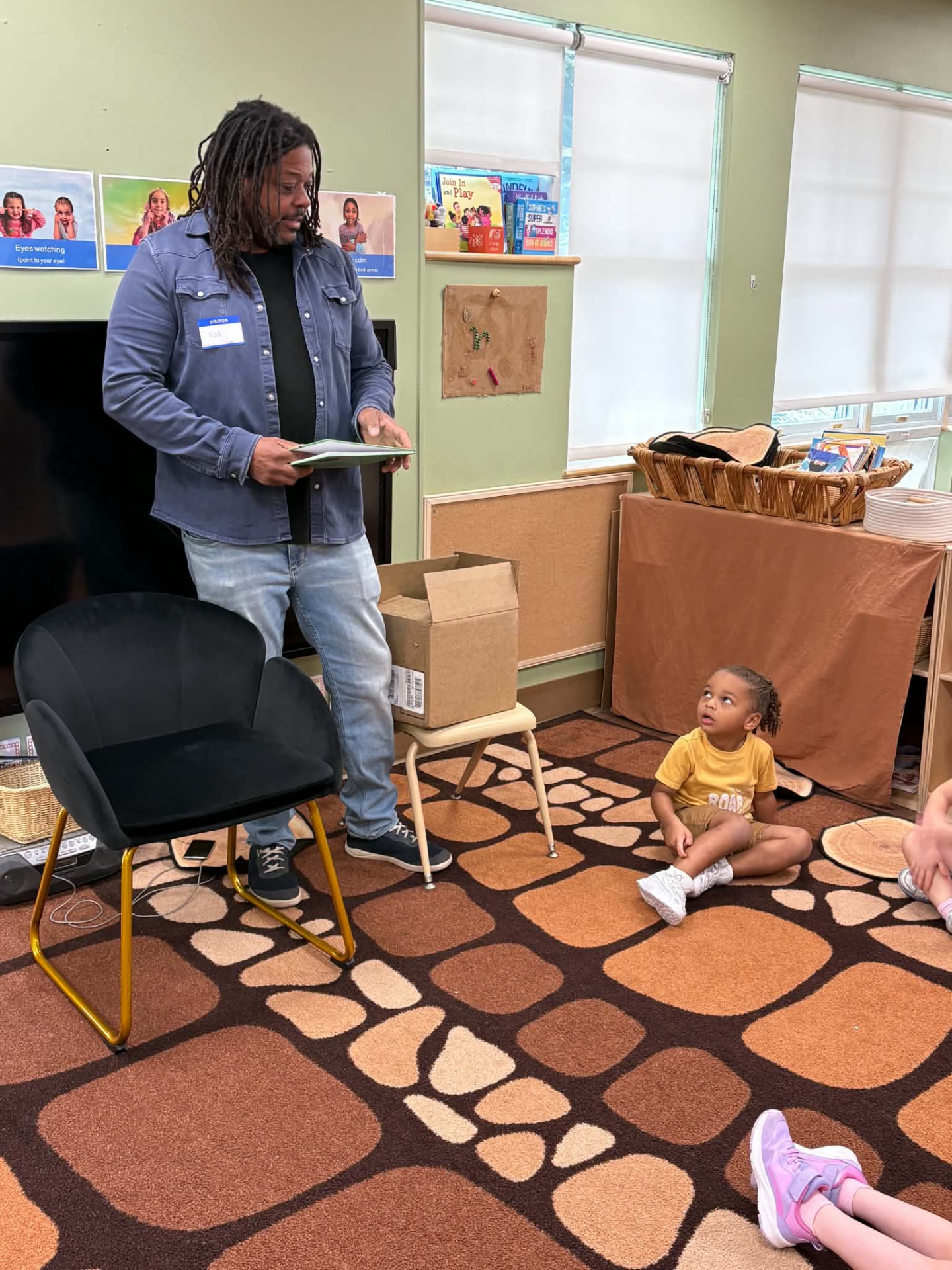 Rod Cornish holding the book in front of a classroom of children